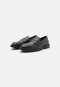 Black leather loafers with a smooth texture, featuring a stitched design and a rubber sole. Slip-on style with no visible hardware.