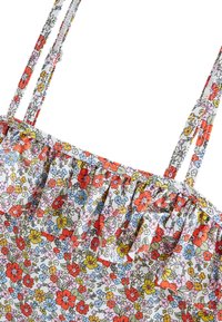 Haut à imprimé floral avec encolure à volants. Présente des fleurs multicolores sur un fond blanc, des bretelles fines ajustables et un tissu léger.