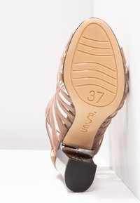 Sandale à talon beige à brides avec semelle en caoutchouc taille 37, talon bloc, et nom de marque "unisa" embossé sur la semelle.