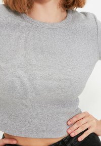 Grå ribbad kortärmad t-shirt med rund halsringning. Tyget verkar mjukt och texturerat med små variationer i stickmönstret.