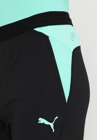 Svarta sportbyxor med en puderskiftande panel. Har en texturerad midja och en liten vit Puma-logotyp på vänster sida.