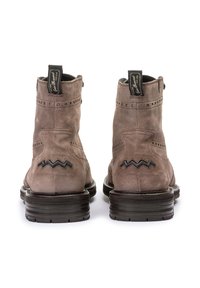 Bottines en daim marron avec des accents en zigzag noirs, des perforations décoratives près du haut et des semelles en caoutchouc contrastantes.