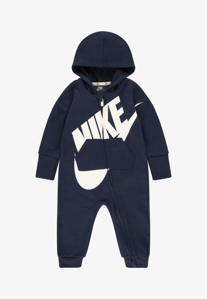 Macacão Nike azul marinho com capuz, fecho frontal, grande logótipo branco e bolso tipo canguru. Tecido suave com punhos canelados.