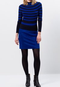 Modrý a černý proužkovaný žebrovaný svetr s vysokým límcem, doplněný hladkou modrou sukní a černými kotníkovými botami na podpatku. Součástí jsou černé punčocháče.