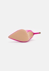 Scarpa con tacco alto fucsia, punta affusolata e tacco sottile, con una parte superiore liscia e una suola beige texturizzata.