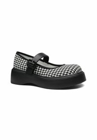 Crna i bijela Mary Jane cipela s motivom houndstooth, s crnim remenom i debelim potplatom, s zaobljenim nosom i teksturiranom gornjištem.