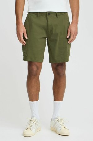 Olijfgroene cargoshorts met een knoopsluiting, zijzakken en een relaxte pasvorm, gecombineerd met witte sokken en crèmekleurige sneakers.