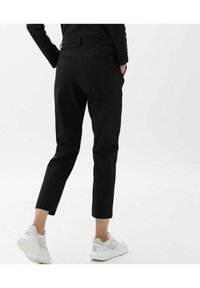 Pantalons noirs à coupe slim et longueur courte. Fabriqués en tissu lisse, avec des poches latérales et une taille standard. Associés à des baskets blanches.