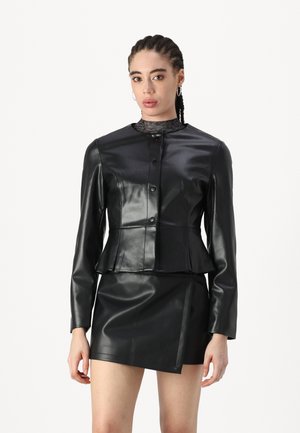 Black faux leather jacket with a high collar, front buttons, and a fitted silhouette, paired with a matching short skirt. Smooth texture.