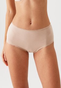 Beige katoen hipster slips met een golvende kantafwerking langs de tailleband en beenopeningen, met een gladde, zachte textuur.