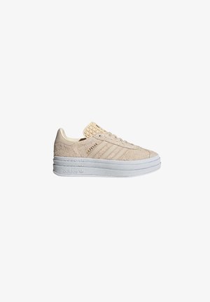 Beige sneakers with a textured suede upper, featuring three white stripes, a woven tongue, and a chunky white rubber sole.