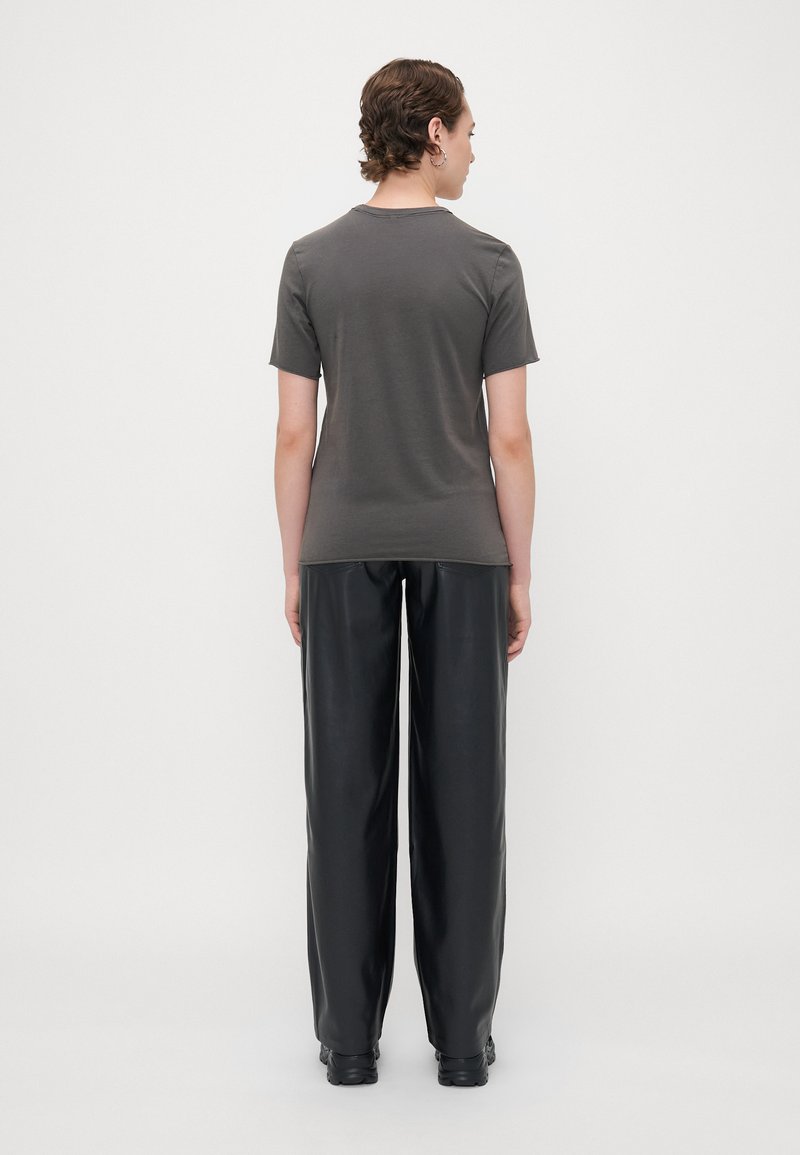 Camiseta ajustada gris, de mangas cortas y cuello redondo, combinada con pantalones de cuero negros holgados, diseño minimalista y textura suave.