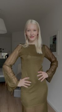 Vestido verde-oliva com corpete justo e mangas transparentes plissadas. O tecido parece liso com detalhes de textura acentuada.