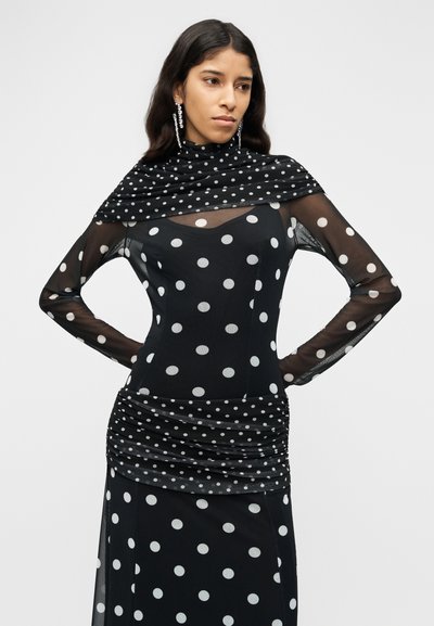 Μαύρο φόρεμα με διαφανή μακριά μανίκια, καλυμμένο με λευκές πουά. Διαθέτει ζώνη στη μέση με ρυτίδες και ντεκολτέ με drape και ομαλή υφή.