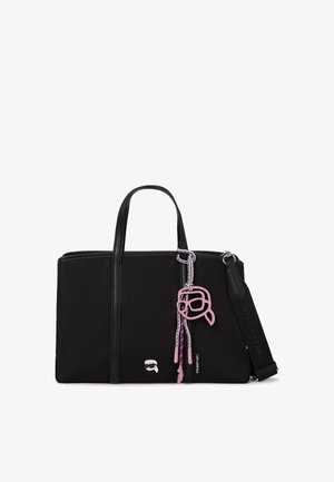 Sac fourre-tout rectangulaire noir avec deux anses, une bandoulière rembourrée amovible, et un porte-clés à visage de dessin animé rose suspendu à une des anses.