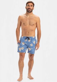 Modré plavky s květinovým vzorem a stahovací šňůrkou v pase, zdobené vzorem světlých květin a zelených listů na jednobarevném modrém pozadí.