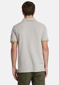 Ljusgrå polo skjorta med en mjuk textur. Har en krage och korta ärmar med gröna detaljer på muddarna. Enkel och ren design.