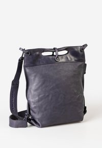Borsa a spalla in pelle di un profondo viola, con una texture liscia, tracolla regolabile e un design distintivo della maniglia superiore. La chiusura presenta accenti intagliati.