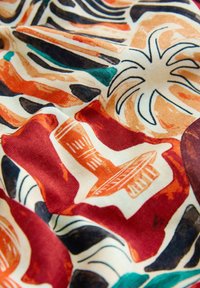 Stoff mit abstrakten Mustern in Erdtönen, mit einer stilisierten Palme und geometrischen Formen in Rot, Schwarz, Beige und Blaugrün.