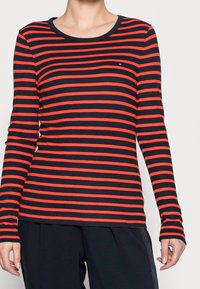 Camicia a maniche lunghe a righe con strisce orizzontali rosse e blu navy, scollatura rotonda e design aderente con texture a coste.