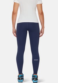 Les leggings de sport bleu marine présentent un design épuré avec des coutures plates et un logo réfléchissant "MAMMUT". Tissu léger et extensible pour un confort optimal.