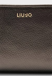 Portefeuille en cuir gris foncé avec une surface texturée et un logo doré "LIU·JO". Design compact avec des lignes épurées et des détails minimalistes.