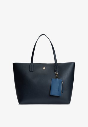 Sac cabas en cuir noir avec longues anses, petit logo doré au centre et pochette bleue zippée avec fermoir attachée.
