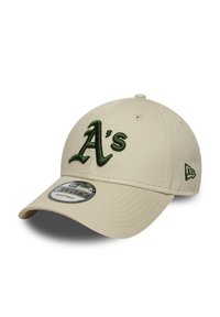 Gorra de béisbol beige con visera curva, que presenta un logotipo bordado en verde de "A's" en el frente y un pequeño acento verde en el lateral.