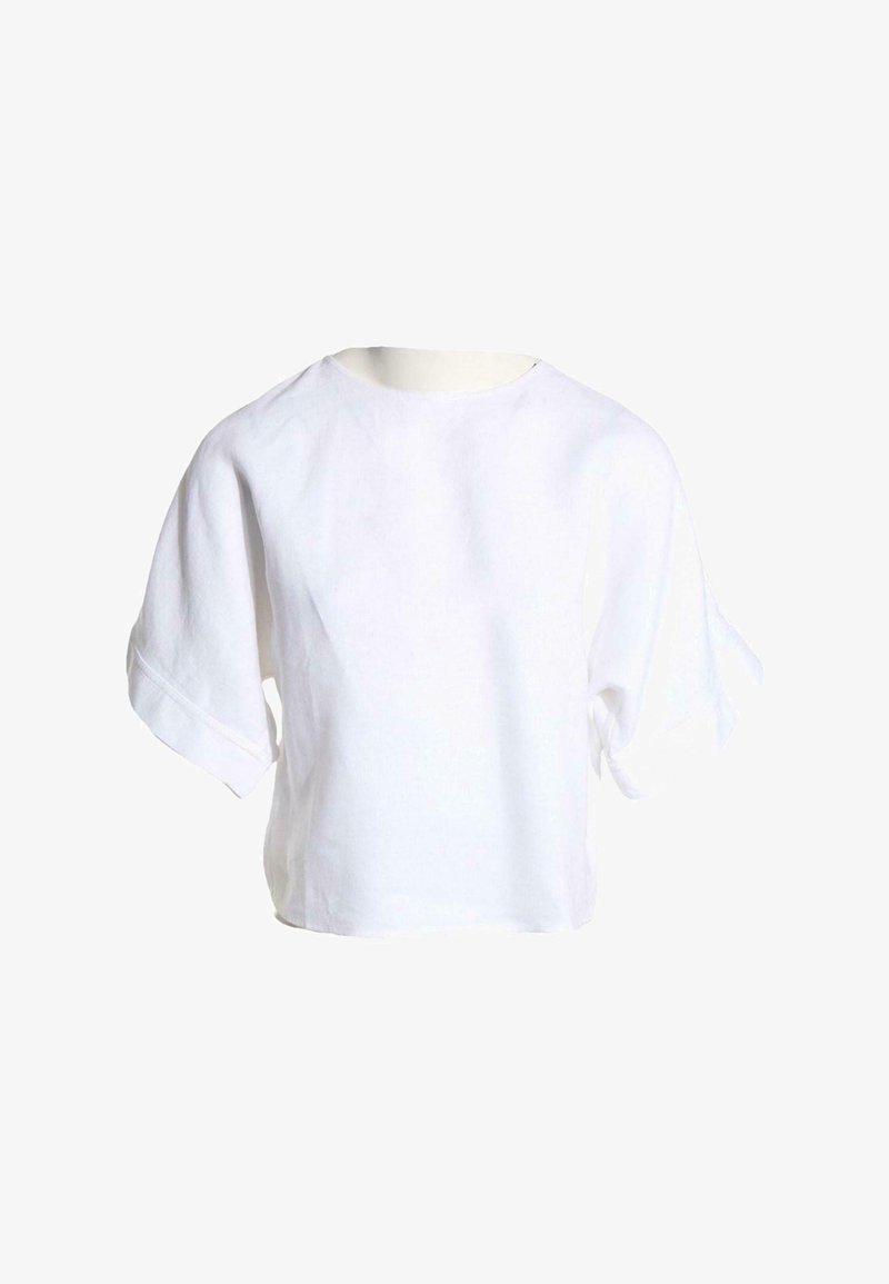 Chemise blanche ample à manches courtes avec encolure ronde et silhouette légèrement carrée sur fond uni.