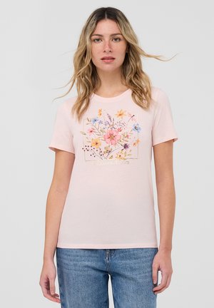 T-shirt di cotone rosa chiaro con un design floreale caratterizzato da fiori multicolori e la scritta "Scegli di Fiorire" all'interno di una cornice decorativa. Maniche corte.