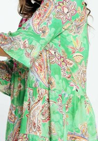 Vestido verde con un patrón paisley en rosa, naranja y crema. Confeccionado en una tela ligera, presenta un diseño en capas y mangas acampanadas.