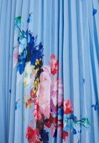 Tessuto plissettato di un blu chiaro con un motivo floreale che presenta fiori rosa, rossi, gialli e blu. Texture morbida e design fluido.