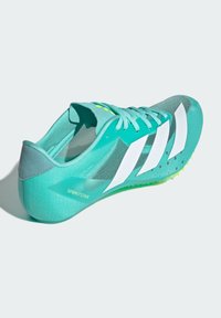 Light blue athletic shoe with white accents, mesh panels, and a green outsole. Features prominent three-stripe design and textured surface.