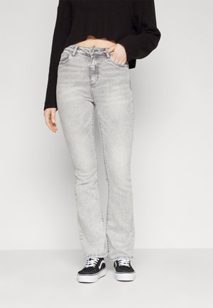 Hoge taille grijze jeans van vervaagd denim, met een rechte pasvorm en lichte slijtage aan de zoom, gecombineerd met zwarte sneakers en een cropped zwart sweater.