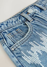 Lyseblå denimshorts med en slidt finish. Har sølvfarvede paljetter arrangeret i et mønster nær lommeområdet. Sølvknaplukning.