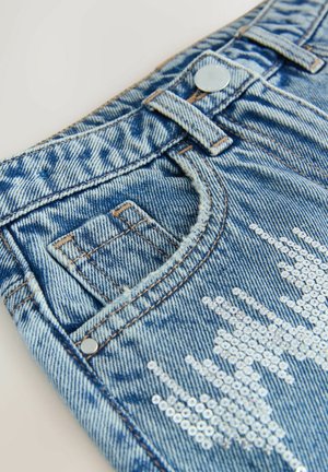 Jeansowe szorty w jasnoniebieskim kolorze z przetarciami. Posiada srebrne cekiny ułożone w wzór w okolicy kieszeni. Zapięcie na srebrny guzik.