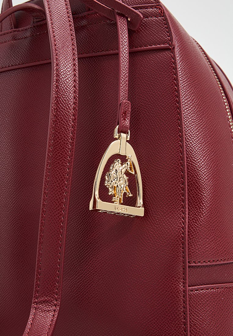 Borsa a mano in pelle bordeaux con una superficie texturizzata, dotata di un ciondolo dorato a forma di staffa con un dettaglio di un cavaliere.