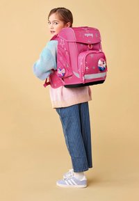 Zaino rosa con motivi a stelle argento, tasche frontali doppie e dettagli riflettenti. Spallacci e base imbottiti per comfort e durata.