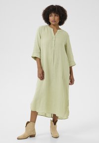 Linen midi haljina u pastelno zelenoj boji, s dugmadi na henley izrezu i rukavima do tri četvrtine. Značajne bočne proreze i teksturirani materijal.