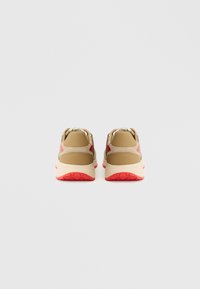 Beżowe sneakersy z czerwonymi akcentami i teksturowaną gumową podeszwą. Konstrukcja ze wzmocnionym piętą i miękką tkaniną. Lekka budowa.