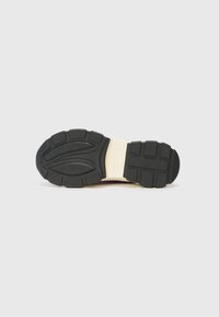 Black rubber outsole with tread patterns, beige midsole, smooth texture, and rounded shape. Suitable for athletic footwear.