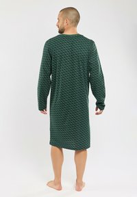 Nuisette verte à manches longues avec un design à motifs. Tissu doux avec de petits accents géométriques. Longueur sous le genou avec un col ras du cou.