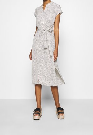 Keve floral midi dress in light fabric, with short sleeves, a V-neck, a tie belt, and side slit. Paired with black platform sandals.