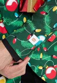 Roheline ülikonna jooks, millel on jõuluehete ja stringitulede mustrid. Omab rohelisi nuppe ja mansetil on silt "OPPO SUITS".