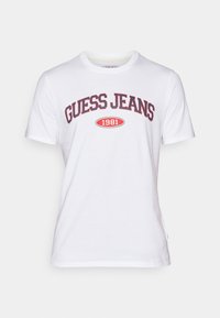 Balta medvilninė T-marškiniai su išlenktu raudonu ir juodu "GUESS JEANS" logotipu, kuriame raudonai parašyta "1981" ovalo formoje. Trumpomis rankovėmis, apvaliu kaklu.