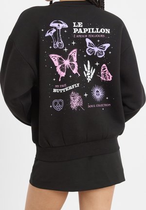 Schwarzer Pullover mit lila und pinkfarbenen Illustrationen von Schmetterlingen, Pilzen, Pflanzen, einem Peace-Zeichen und Texten wie „Le Papillon“ und „My Fave Butterfly“.