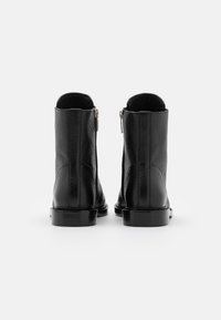 Czarne skórzane botki za kostkę o teksturowanym wykończeniu, z zamkiem błyskawicznym z tyłu i solidną czarną podeszwą.