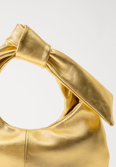 Guldfarvet metallic taske med en knyttet hank. Har en glat tekstur og et foldet design, der fremhæver en cirkulær åbning for nem adgang.
