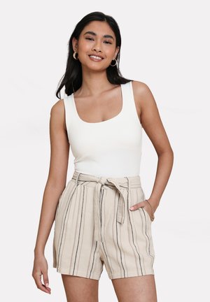 Body bianco senza maniche abbinato a pantaloni corti beige a righe con vita cintata e tasche laterali, tessuto dalla trama liscia.