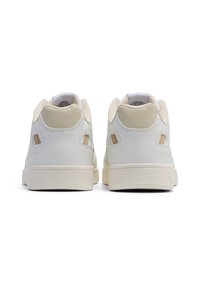 Białe skórzane sneakersy z beżowymi akcentami, z gładką fakturą, wyściełanym kołnierzem i wycięciami na pięcie. Płaska gumowa podeszwa.